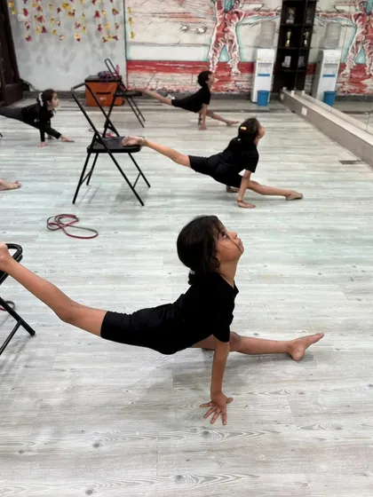 A close-up on a young dancer's form during a supported split, showing the grace and control developed in our classes.