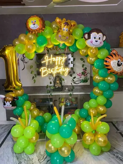 A simple yet beautiful jungle-themed balloon ring for a first birthday at home. This setup uses a neon 'Happy Birthday' sign and foil balloons of a lion, monkey, tiger, and giraffe.