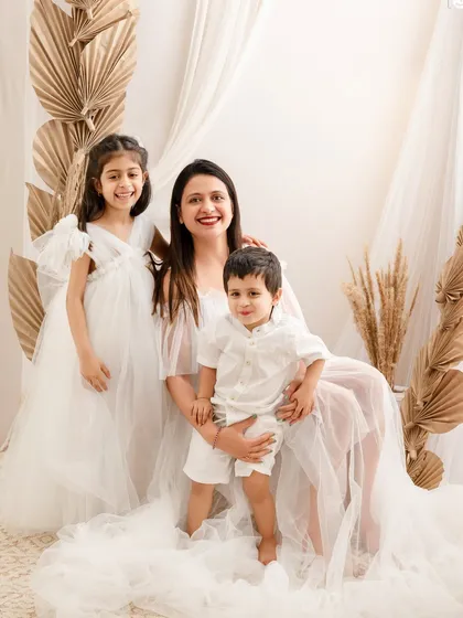 A mother's love is boundless. This portrait captures a mom with her two children, all dressed in white, in a serene and beautiful setting.