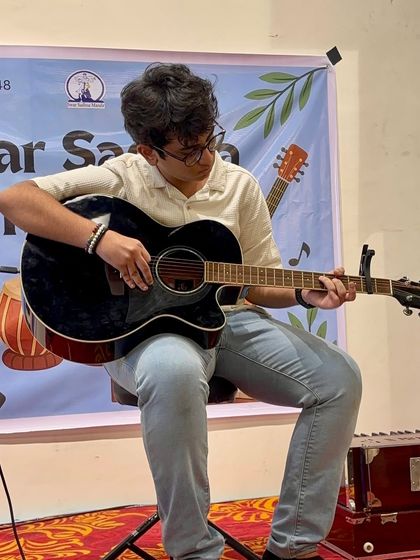 A student uses a capo to play a complex piece, showing the technical skills learned in our classes. We cover all aspects of guitar playing, from basic chords to advanced techniques.