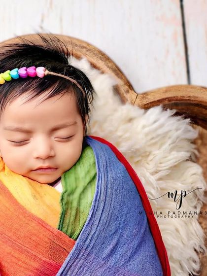 A close-up on the baby's face, showing their rainbow-beaded headband.