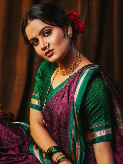 A powerful close-up, with the model looking directly at the camera. The lighting highlights her features and the rich colors of the saree.