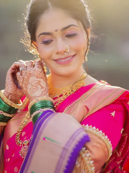 Adjusting her earring, this shot captures the elegance of the bride. The soft lighting highlights her flawless makeup and the beautiful details of her saree and jewelry.