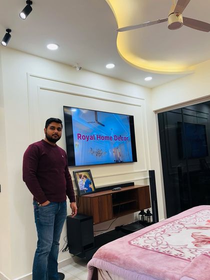 A look at a completed master bedroom in Nirala Estate, with a simple TV unit, elegant false ceiling, and a comfortable bed.