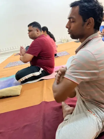 Participants hold a posture with closed eyes, turning their focus inward during a guided Surya Kriya session.
