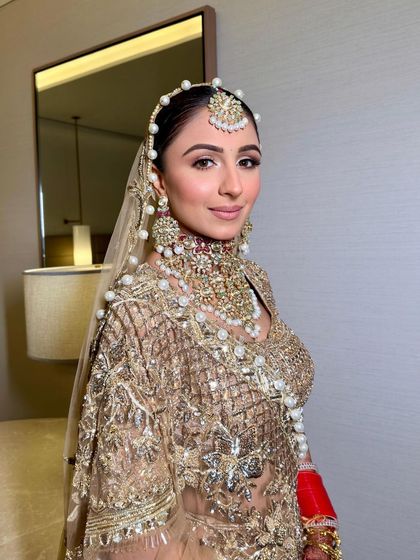 The complete bridal look. The soft makeup perfectly complements the intricate gold embroidery and the statement pearl jewelry.