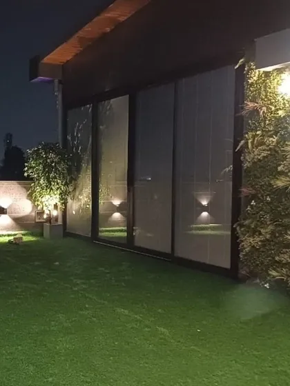 A view of a completed terrace at night, highlighting the vertical garden and ambient wall lighting. We ensure our spaces are just as beautiful and functional after the sun goes down.