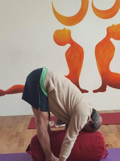 A supported forward fold using a bolster. This restorative variation of Uttanasana helps to calm the nervous system and release tension in the back.