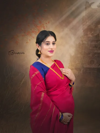 A beautiful studio portrait of a mother-to-be in a red saree, with a soft, artistic background.