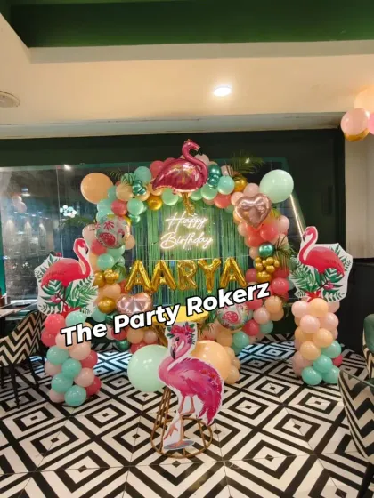 A stylish Flamingo-themed party setup in a restaurant. The tropical balloon arch, flamingo cutouts, and neon sign look fantastic against the venue's modern decor.