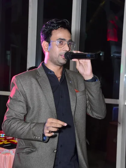 Addressing the audience at a party, microphone in hand. I keep the energy high and the atmosphere fun.