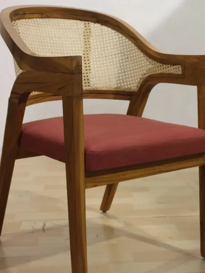 A front view of the trending teak and cane armchair. The curved back provides excellent support, making it a comfortable choice for long conversations.