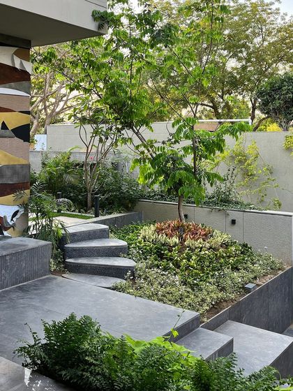 This small garden bed uses a rich palette of foliage colors and textures, from deep reds to bright greens. The stepped pathway invites you into the space, which is detached from the main garden to create a special moment.