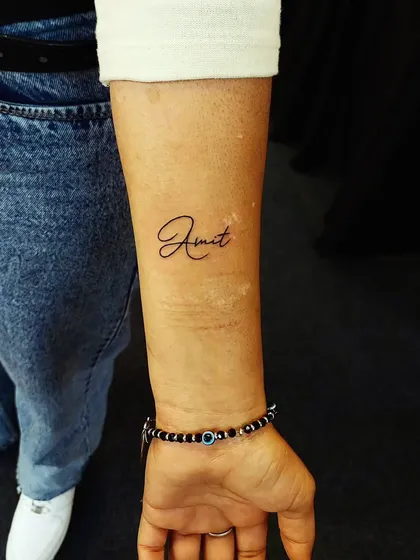 A simple and elegant name tattoo, 'Amit', in a clean cursive script. A perfect way to honor someone special.