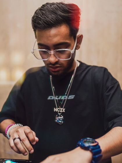 A close up shot of me at the decks, showcasing my custom 'NCIX' chain and watch. My accessories are a key part of my artist identity.