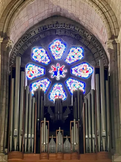 A stunning stained-glass rose window set against ancient stone and massive organ pipes in a European cathedral. The contrast of color, material, and scale is breathtaking. It’s a lesson in creating dramatic focal points within a grand space.
