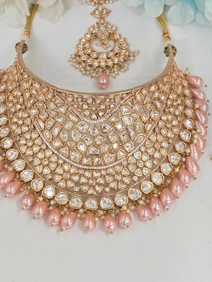 A beautiful, wide bridal choker with pink pearl drops, displayed to show its intricate design and craftsmanship.