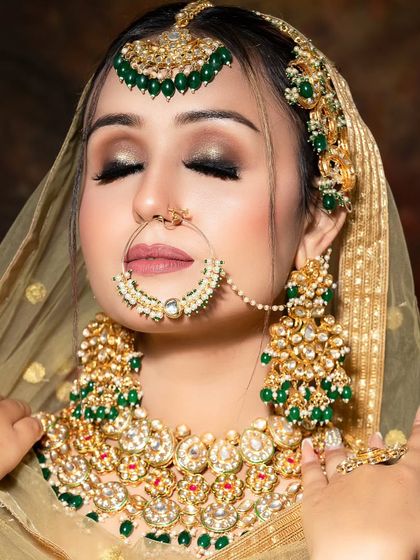 A bride in a golden lehenga, adorned with a heavy Kundan and green bead jewellery set. The closed-eye pose creates a serene and beautiful portrait.