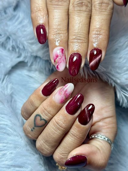 A gorgeous mix of deep wine red, a shimmering cat eye effect, and a delicate pink and white marble accent nail.