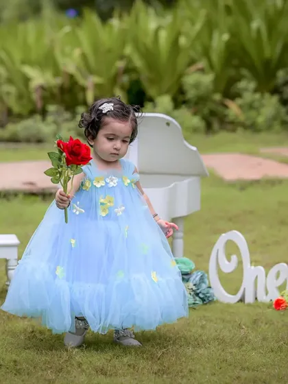 A simple red rose for a little princess on her first birthday. The soft, natural light of the park setting complements her delicate blue dress, making for a dreamy and timeless portrait.