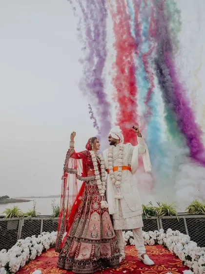 A spectacular varmala moment with a blast of rainbow-colored smoke against the sky. This is how I create modern, vibrant, and unforgettable wedding memories.