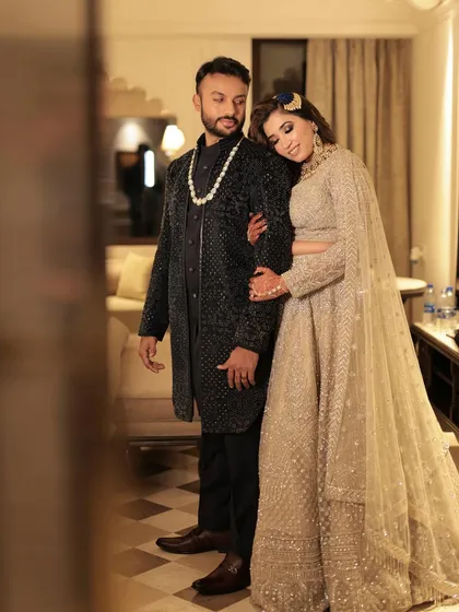A candid moment between the bride and groom at their sangeet. Her makeup is glamorous yet soft, with a focus on a shimmering smokey eye and a radiant complexion.