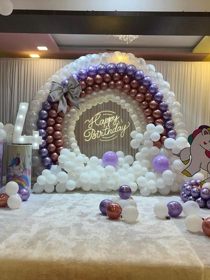 A magical unicorn and rainbow theme for a 4th birthday. I created a beautiful rainbow arch with metallic and purple balloons, complete with fluffy white clouds and a unicorn cutout. The light-up number '4' adds a special touch to this dreamy setup.