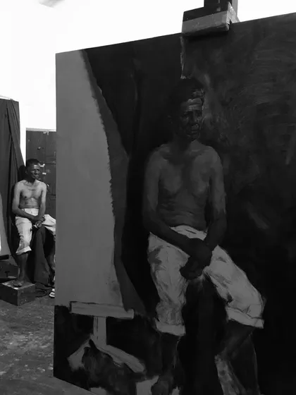 A work-in-process shot of a monochrome oil painting, showing the initial blocking-in of the figure and background.