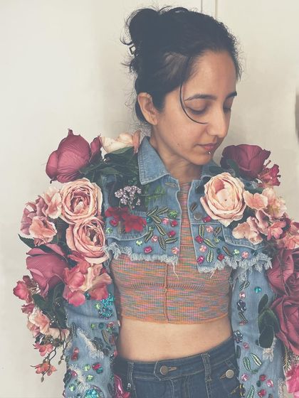 A detailed shot of the custom floral denim jacket. You can see the combination of hand-sewn beads and a variety of silk roses and blossoms that create a lush, textured effect.