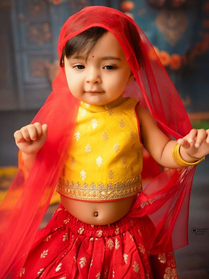 A close-up of a little girl in her festive outfit. The delicate red veil and her sweet expression make this a truly special photograph.