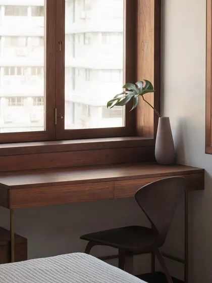 This built-in study desk is designed to maximize a compact space without sacrificing style. Crafted from warm wood and supported by slender brass legs, it feels both light and fully integrated with the window nook.
