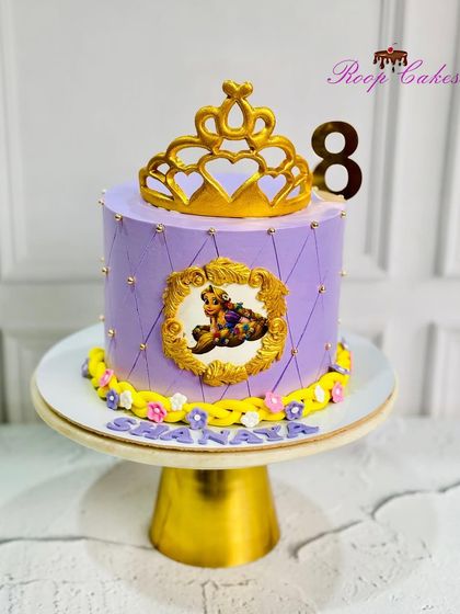 A royal Rapunzel-themed cake for an 8th birthday. This purple cake is decorated with a golden tiara and a portrait of the princess in an ornate frame.