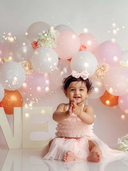 Clapping with joy for her first birthday. The fairy lights in the background add a magical sparkle to the celebration.