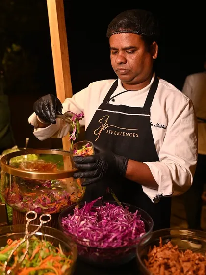 A member of our culinary team carefully assembles individual salad cups at a live station, ensuring each serving is fresh and beautifully presented.
