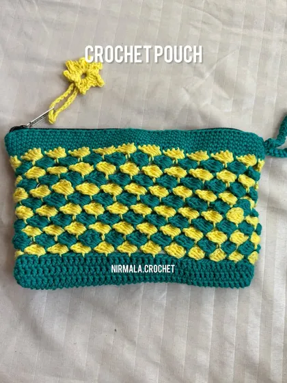 This green and yellow crochet pouch showcases a beautiful scale stitch, giving it a unique texture and durability. It comes with a matching flower zipper pull.