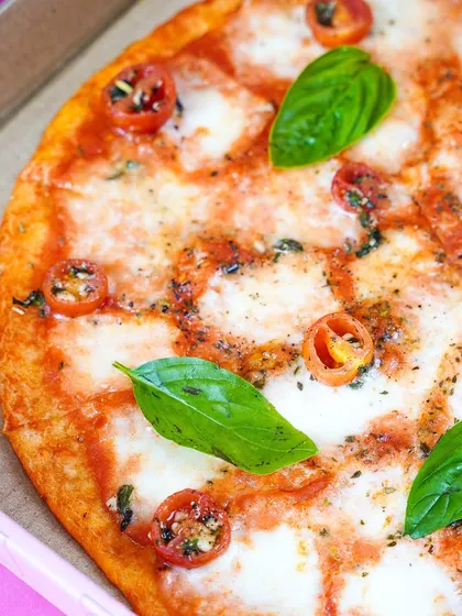 A close-up shot of a classic Margherita pizza, focusing on the melted cheese and fresh basil. The bright, vibrant colors make this simple pizza look incredibly appetizing.