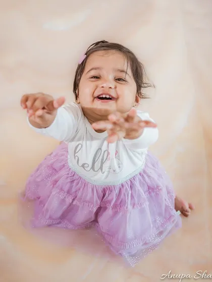 An expressive photo of a baby reaching towards the camera with a big, happy smile. This engaging shot makes you feel like you're right there in the moment.