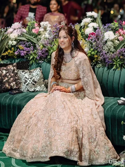 A happy bride at her reception in a sparkling blush pink Anushree Reddy lehenga. The styling is all about glamour and celebration.