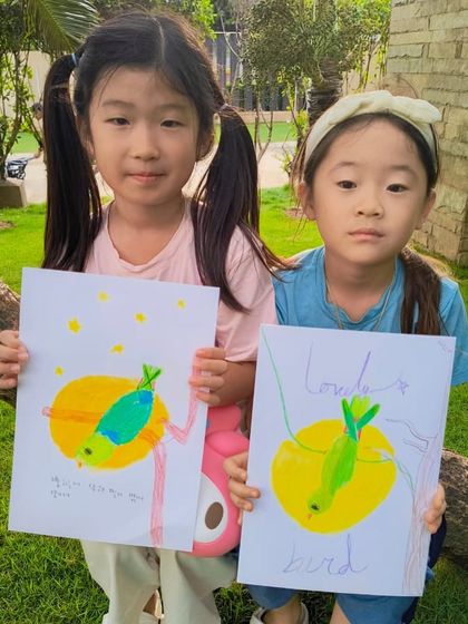 A duplicate image of two students from our parrot class holding up their colorful creations, each with its own unique charm.