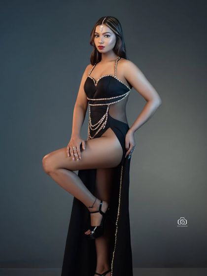 A dynamic pose in a black, pearl-embellished gown. The studio lighting highlights the intricate details and the model's strong form, making for a striking and sophisticated fashion portrait.