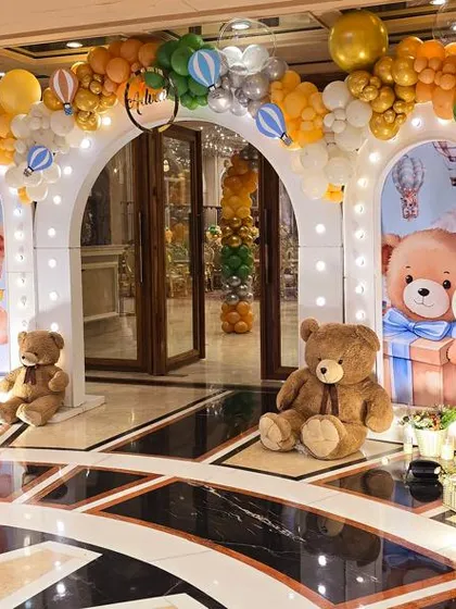 An enchanting hot air balloon and teddy bear themed entrance, with multiple arches and props creating a magical pathway.
