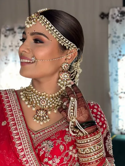 A side profile showcasing the intricate details of the bridal jewelry, nath, and the flawless makeup application that enhances the bride's features without overpowering them.
