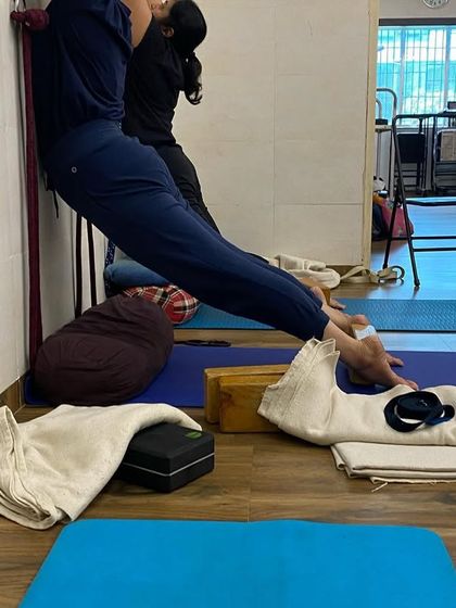 Using the wall and props for a supported stretch. This variation helps to decompress the spine and lengthen the back of the legs safely.