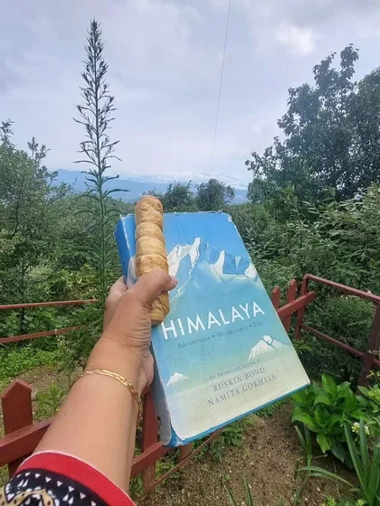 A book about the Himalayas, enjoyed with a local snack, against the backdrop of the Himalayas themselves. A truly immersive reading experience.