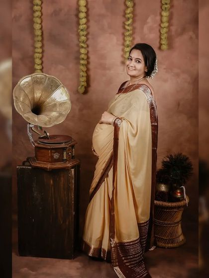 A standing pose that beautifully showcases the baby bump and the elegant drape of the saree. This is another lovely shot from our nostalgic, vintage-themed maternity session.
