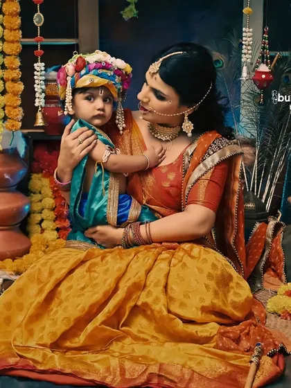A mother holds her little Kanha in our richly decorated Janmashtami studio. The warm, deep colors create a dramatic and beautiful portrait.