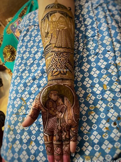 A close-up of a detailed bridal mehndi design. The palm features a romantic couple portrait, which flows into a full arm design depicting another couple scene under a traditional archway.