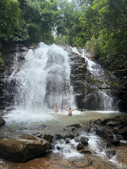 Two trekkers enjoying a moment of peace and fun in the cool waters of a waterfall pool in Uttara Kannada.