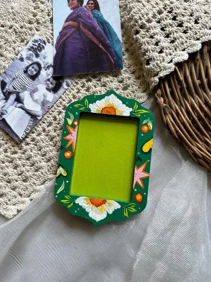 A floral-themed photo frame magnet, with white flowers against a bold green background.