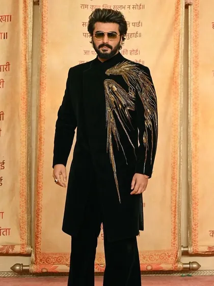 A celebrity-worn black velvet indowestern piece featuring a striking gold embroidered wing on one shoulder. This design is perfect for making a dramatic entrance at a reception or awards night.